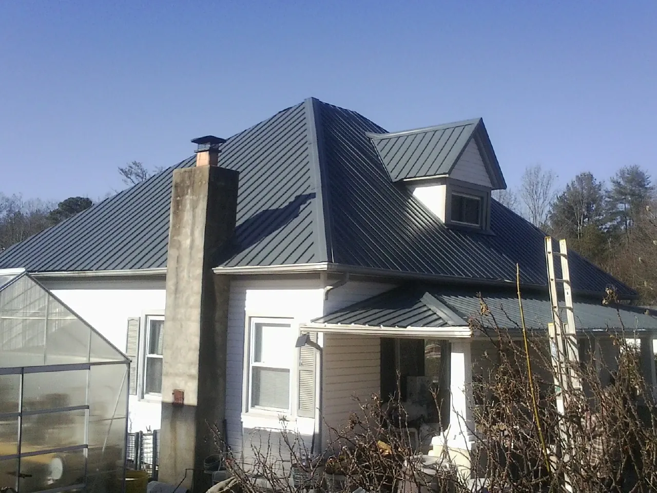 Dark blue standing seam metal roof on a white farmhouse with dormer — Slate & Tile Roof Repair by Roofing Brothers in Combined Locks