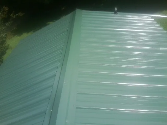 New green metal panels meeting at the ridge of a roof — Flat Roof Repair work by our crew in Combined Locks