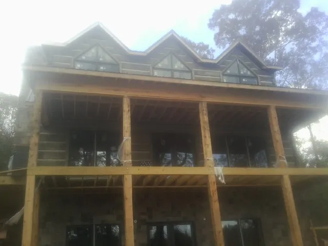 Dormers and porch framing on a large log home under construction — Roof Coating work by our crew in Combined Locks
