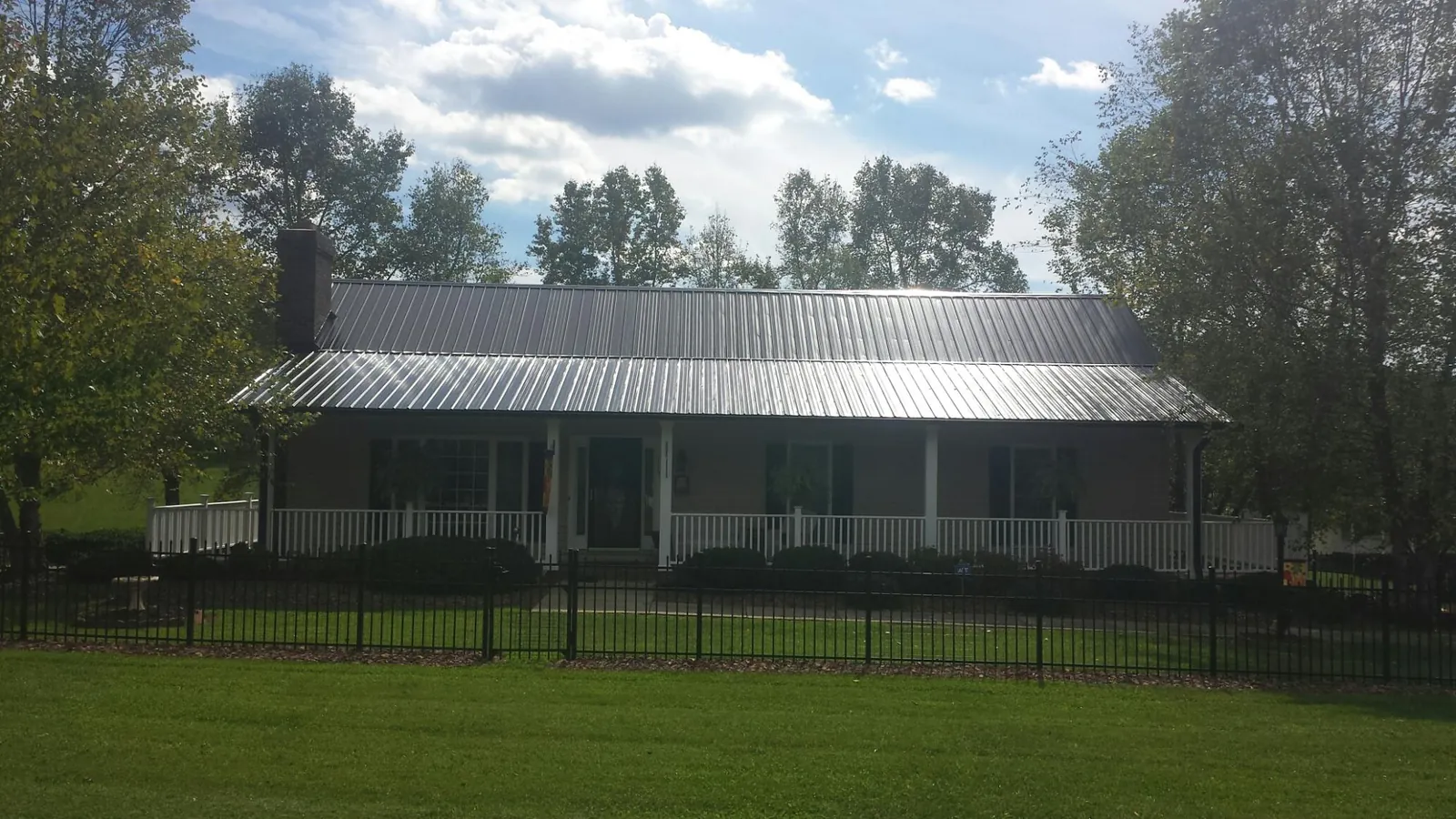 Gray metal roof on a brick ranch with a full width front porch — Gutter Guard Installation work by our crew in Combined Locks