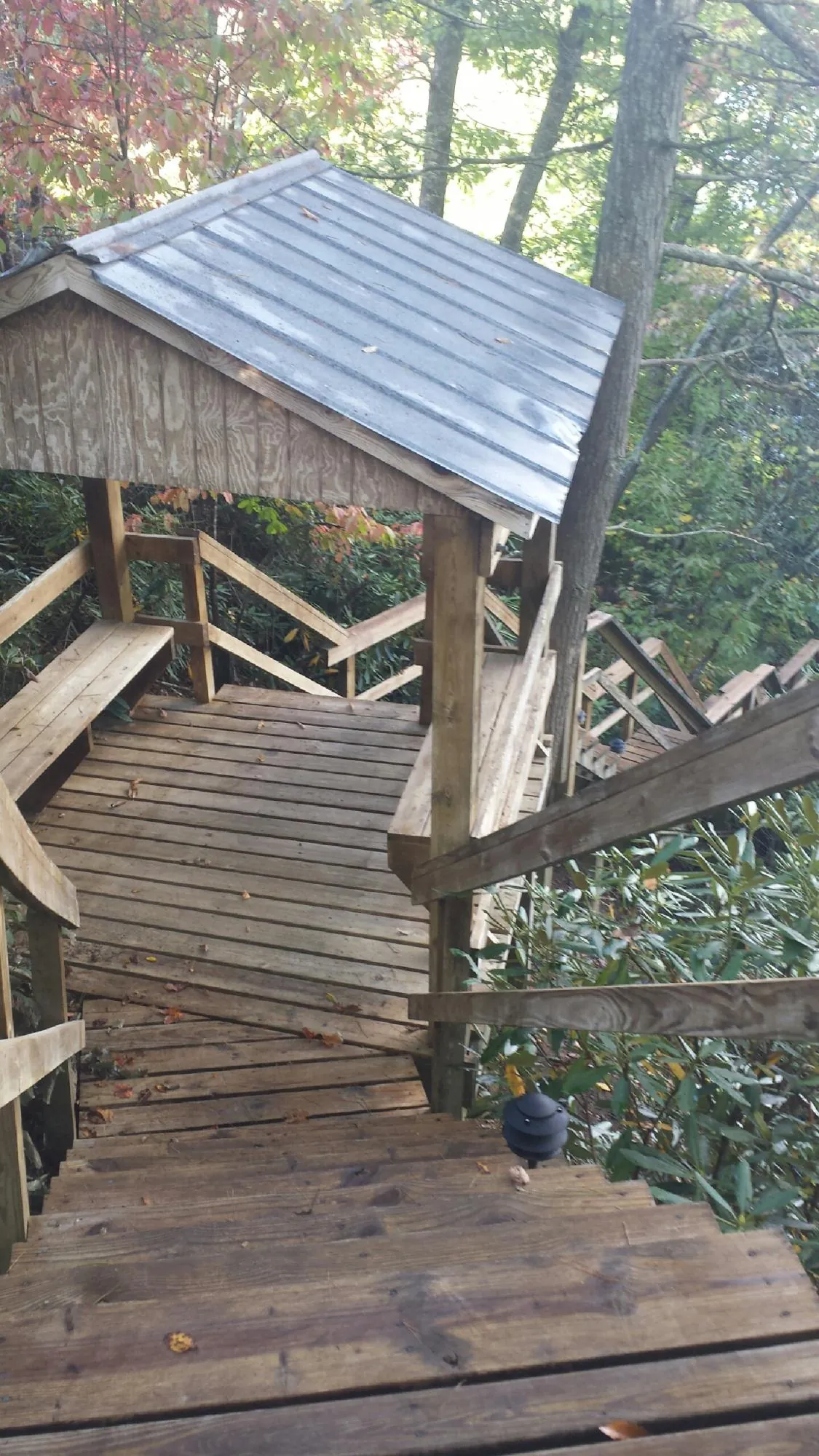 Metal roofed shelter over wooden steps on a wooded walkway — Skylight Repair & Installation work by our crew in Combined Locks