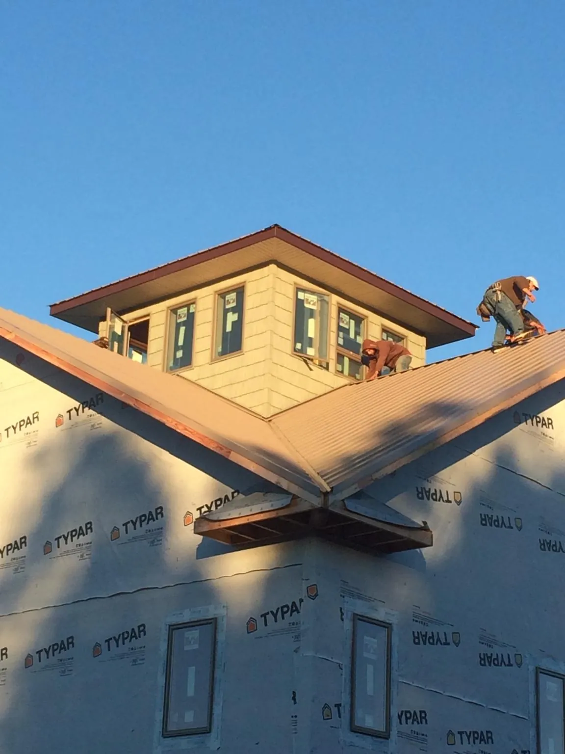 Roofers working around a rooftop cupola on a new metal roof at sunset — Roof Waterproofing in Combined Locks by Roofing Brothers